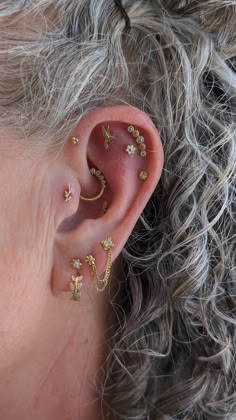 a close up of a person's ear with gold piercings on top of it