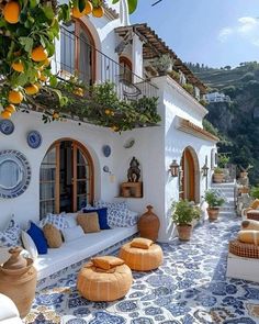 an outdoor living area with oranges and potted plants on the roof, along with white furniture