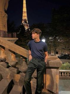 a man is standing on some steps in front of the eiffel tower at night