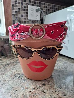 a cup that has some kind of hat on top of it with sunglasses and a ring