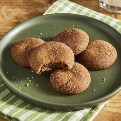 some cookies are on a green plate next to a glass of milk and a napkin