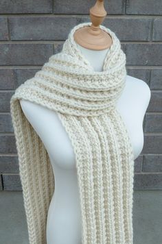 a white knitted scarf on a mannequin with a brick wall in the background