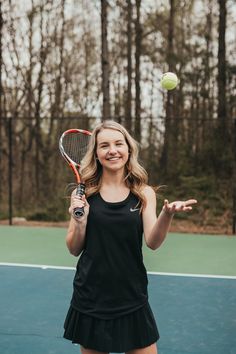 a young woman holding a tennis racquet on top of a tennis court with a ball in the air