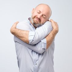 a bald man with his eyes closed and hands on his chest, leaning against the back of his head