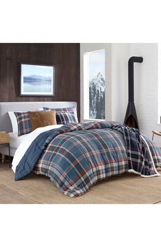 a bed with plaid comforter and pillows in a room