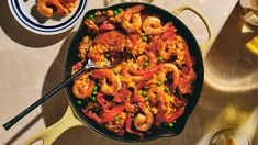 a skillet filled with shrimp, peas and rice