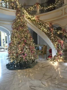 a christmas tree in the middle of a large room with stairs and lights on it