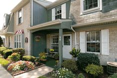 an apartment building with landscaping and flowers in the front yard