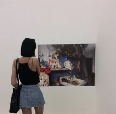 a woman standing in front of an art work on the wall with her back to the camera