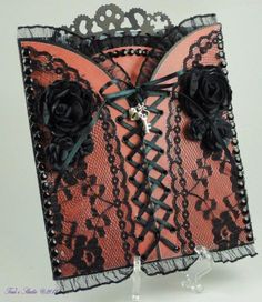 an orange and black lace card with roses on the front is attached to a clear stand