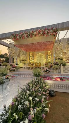 an outdoor wedding setup with flowers and greenery on the stage at sunset or dawn