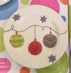 a white plate topped with ornaments on top of a colorful table cloth next to a knife and fork