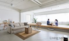 a living room filled with furniture and people sitting on the couches in front of a window