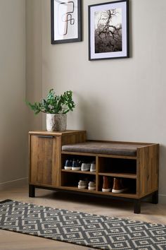 a wooden bench sitting next to a wall with pictures on the wall and a potted plant in front of it