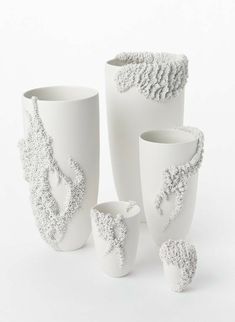 three white vases with designs on them sitting next to each other in front of a white background