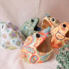 four ceramic birds sitting next to each other on a white surface with flowers in the foreground