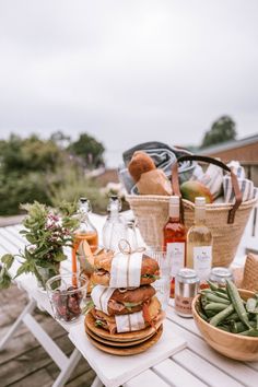 a picnic table with food and drinks on it, along with two wicker baskets