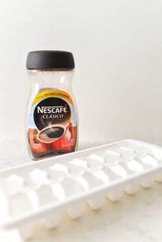 a bottle of coffee sitting on top of a white table next to a computer keyboard