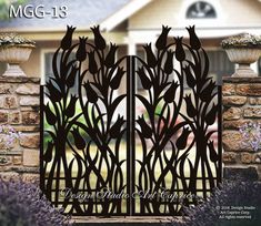 an iron gate in front of a house with purple flowers and bushes behind it,