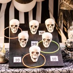 a table topped with lots of fake skulls on top of a black and white table cloth