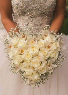 a bride holding a bouquet of white roses