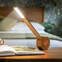 a wooden desk lamp sitting on top of a table next to an open book and coffee cup