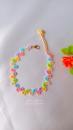 a colorful bracelet with beads and a flower on it next to a pair of scissors