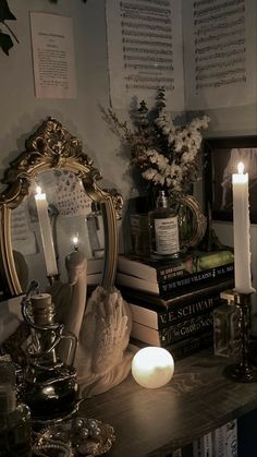 a table topped with lots of books next to a mirror and lit candles on top of it