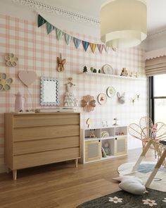 a child's room with pink and white checkered wallpaper, wooden furniture and toys