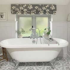 a white bath tub sitting in a bathroom next to a window with flowers on it