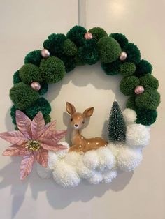 a christmas wreath with poinsettis and a deer in the middle is hanging on a wall