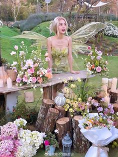 a woman in a fairy costume standing on a table with flowers and candles around her