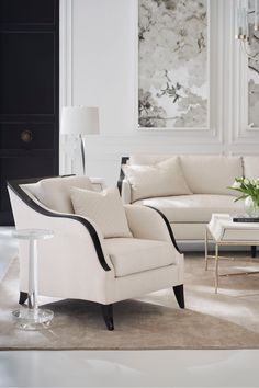 an elegant living room with white furniture and art on the wall behind the couches