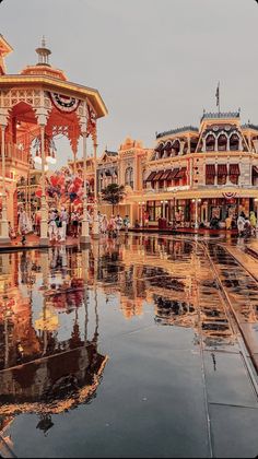 an amusement park with many rides and people walking around the area on a rainy day