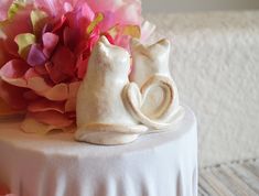 a white cake with flowers and a cat figurine on top