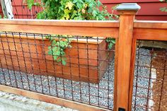 a wooden fence with metal bars on it and plants growing in the planter box