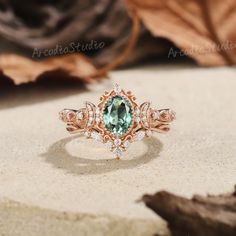 an engagement ring with a green stone surrounded by diamonds