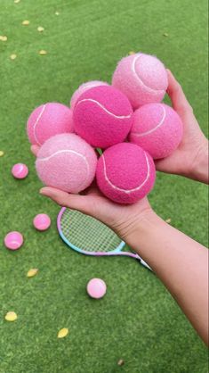 a person holding a bunch of pink tennis balls