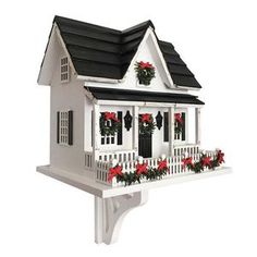 a white birdhouse with red flowers and wreaths on the roof is decorated for christmas