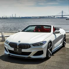 a white bmw z4 convertible parked next to the water