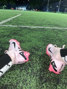 two pairs of pink and black soccer cleats sitting on the field at night