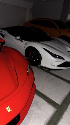 three different colored sports cars parked in a parking garage with white and red one on the floor