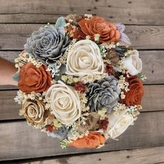 a bridal bouquet made up of flowers and succulents on a wooden background