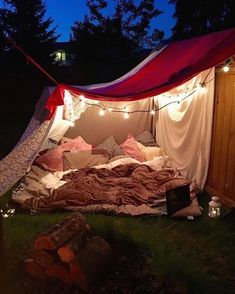 a bed in the middle of a yard with lights strung from it's sides