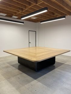 an empty room with a square wooden table in the middle