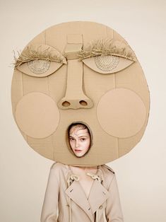 a woman standing in front of a cardboard face