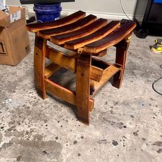 a wooden stool sitting on top of a floor next to a box and some boxes