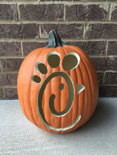 a carved pumpkin with the letter g on it's face and paw print, sitting in front of a brick wall