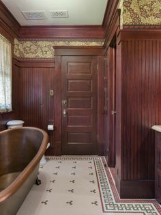 a bathtub and sink in a bathroom with wood paneling on the walls, along with a wooden door