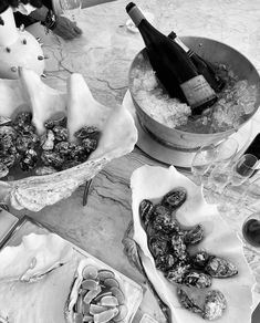 a table topped with wine bottles and oysters next to other dishes filled with food